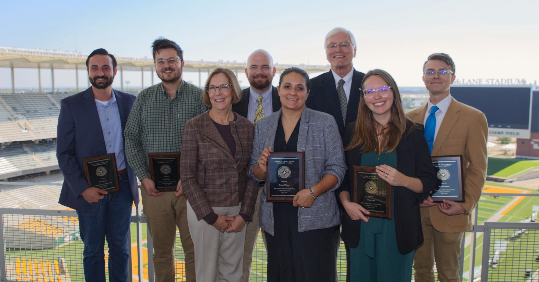 The 2023  Outstanding Graduate Student Instructor Award Winners stand with Provot Nancy Brickhouse and Graduate School Dean Larry Lyon with the McLane Stadium field in the background