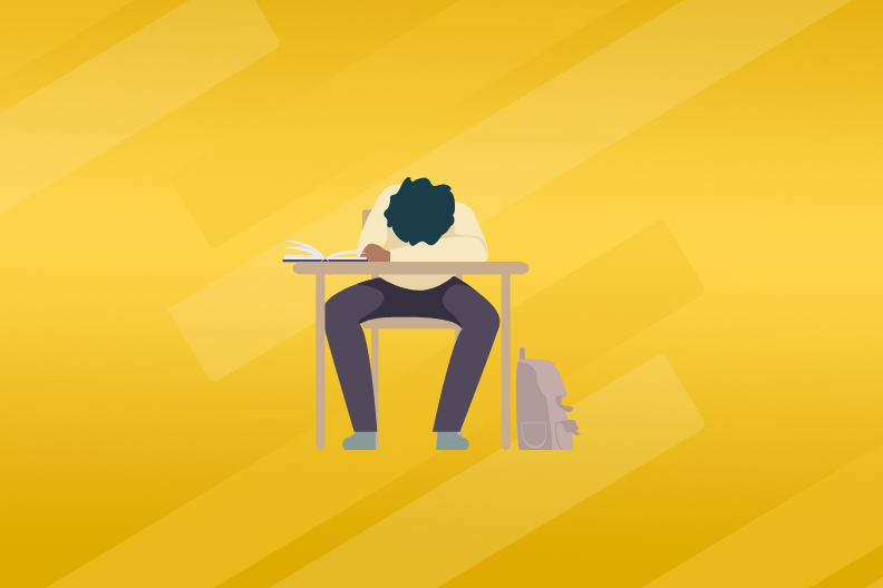 a student slumps over his desk with his head facing down on his folded arms
