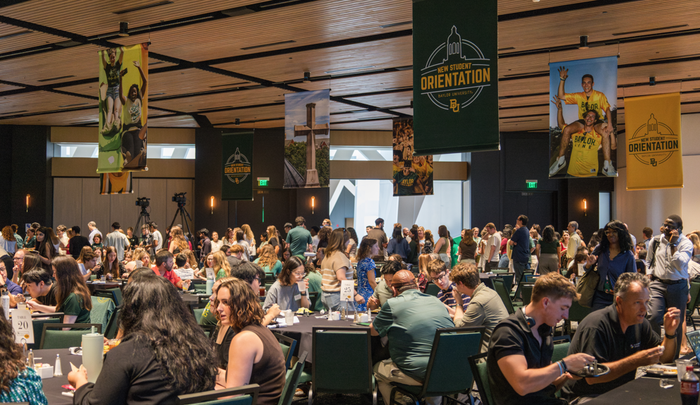 welcome banners hang above students eating lunch at round tables
